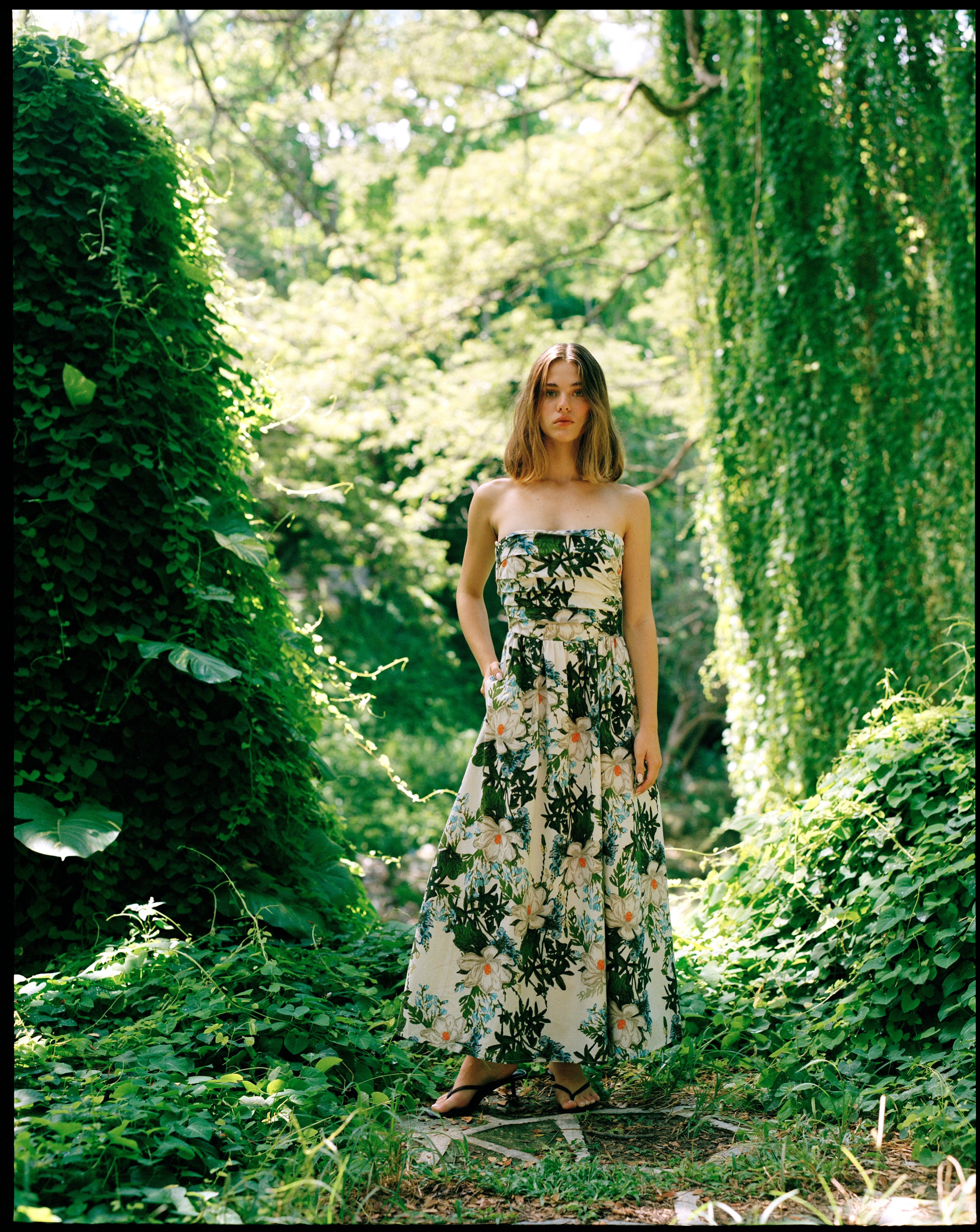 Woman in a floral dress standing in a lush green garden